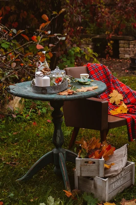 Drewniany stół na przytulnym patio z jesiennymi liśćmi i kubkami