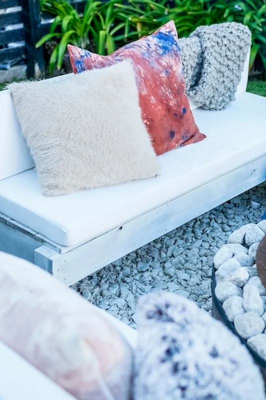 Kanapy i ławki z poduszkami przy kominku w ogrodzie