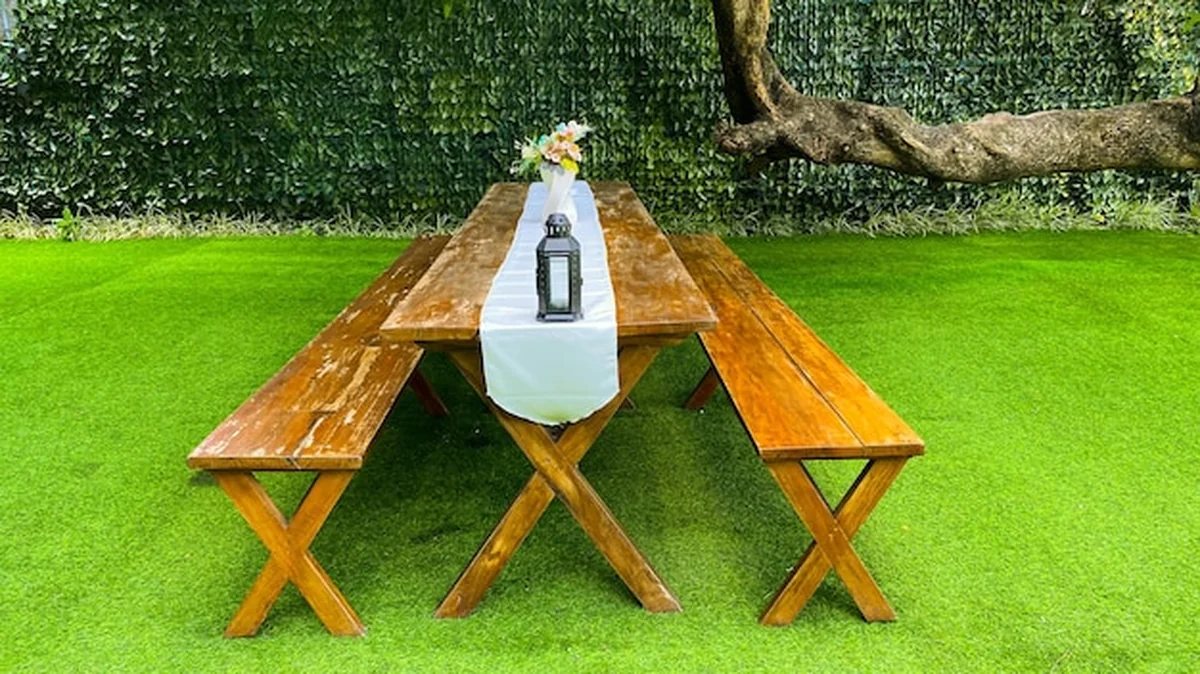 Drewniany stół i dwie ławki na zielonym trawniku gotowe do pikniku na świeżym powietrzu