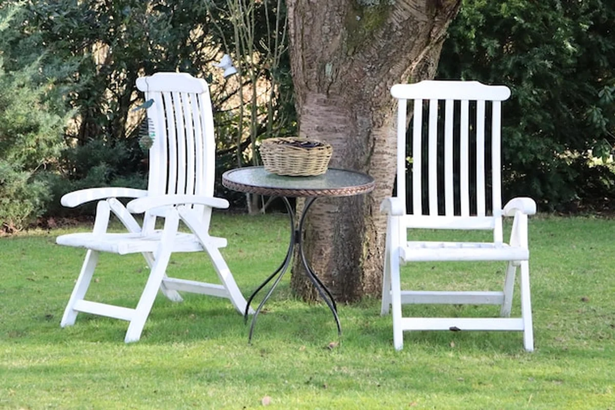 Ogród z białymi krzesłami i stołem pod drzewem