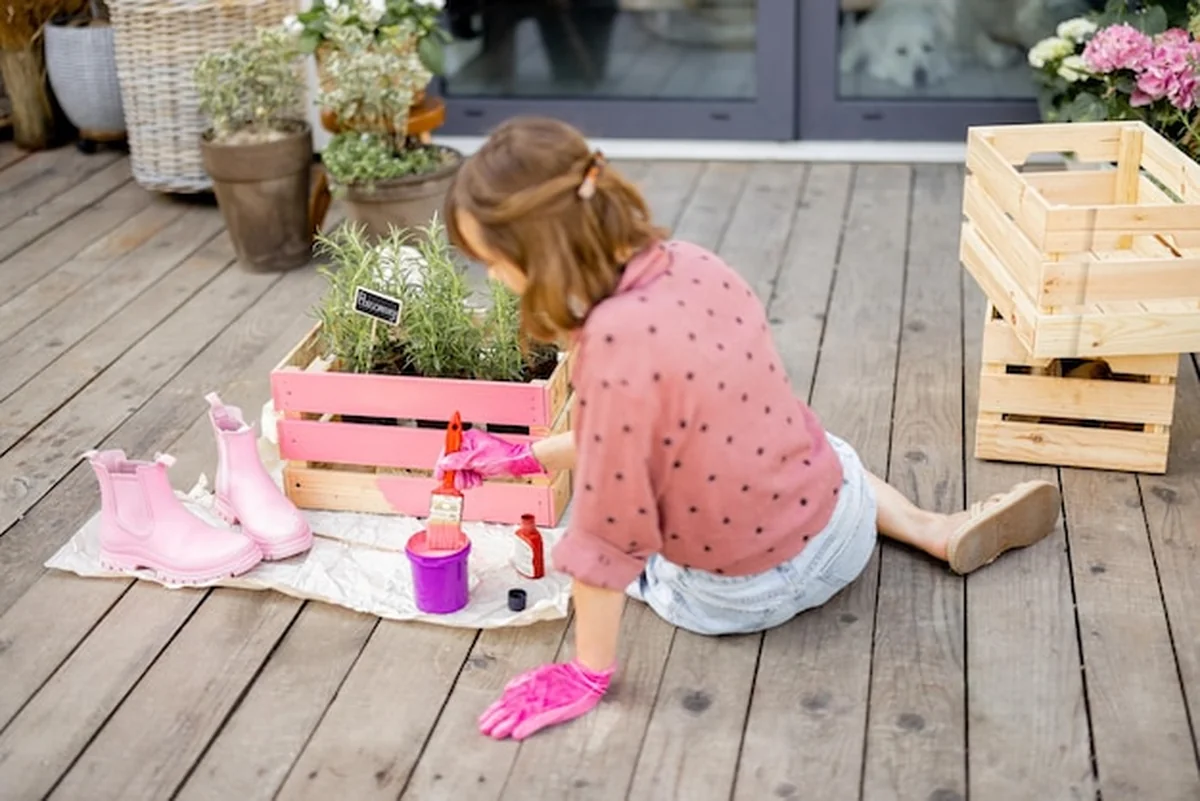 Kobieta malująca drewniane pudełko na zewnątrz