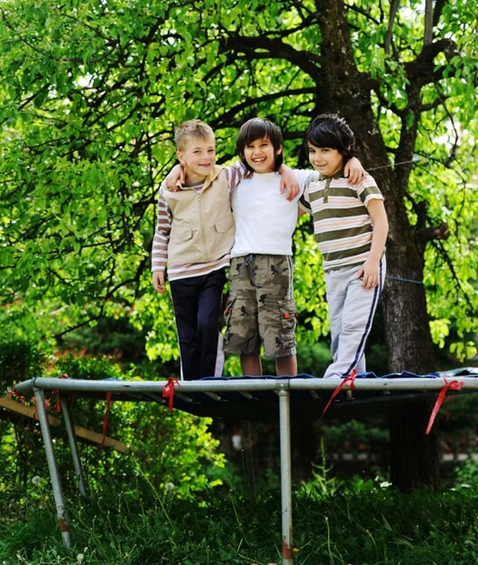 Szczęśliwe dzieci bawiące się na trampolinie w ogrodzie