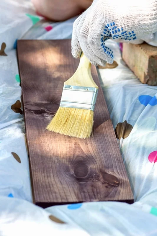 Osoba w rękawiczce maluje deskę pędzlem