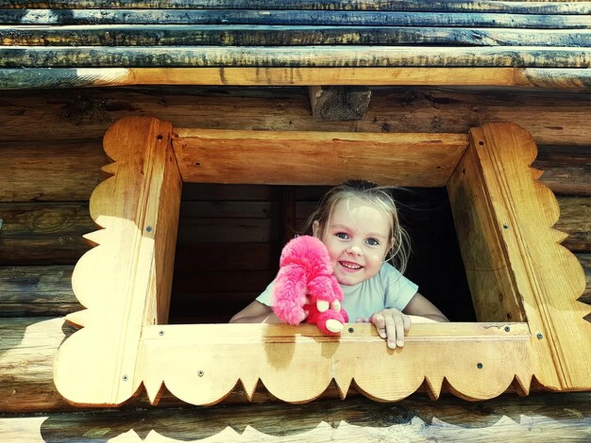 Uśmiechnięta dziewczyna trzymająca zabawkę, patrząca przez okno