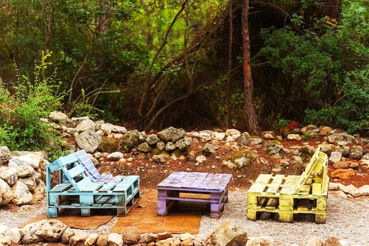 Dwa kolorowe krzesła i stół z drewnianych palet w ogrodzie