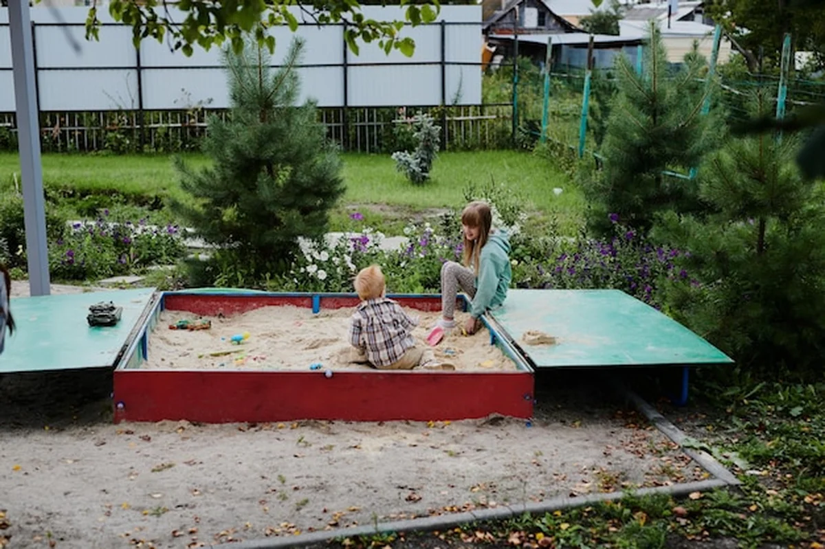 Dzieci bawiące się w piaskownicy na placu zabaw w ogrodzie