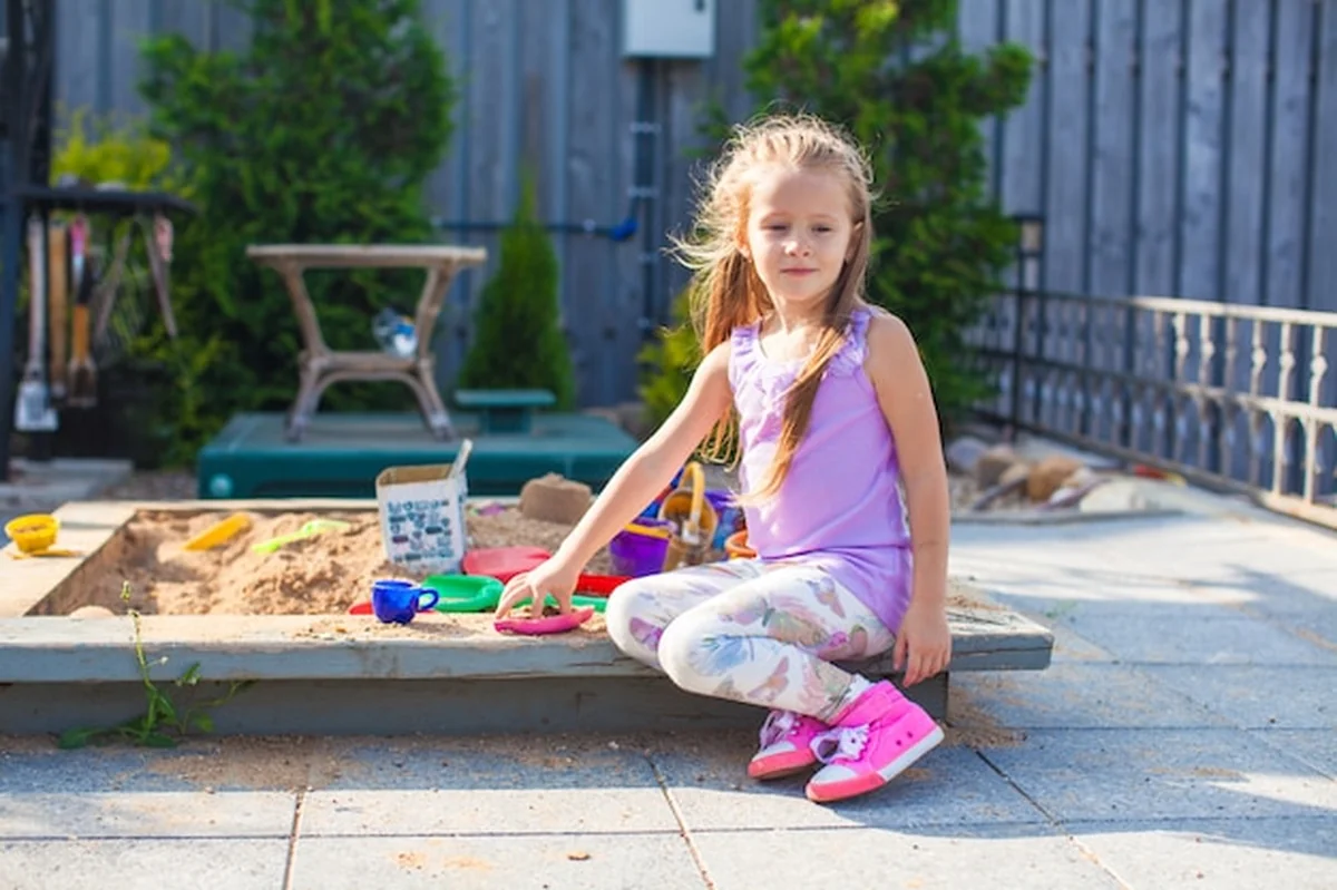 Dziewczynka bawi się przy piaskownicy z zabawkami