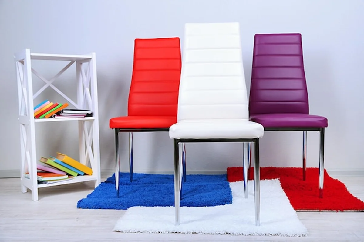 Nowoczesne kolorowe krzesła z książkami na drewnianym stojaku przed ścianą