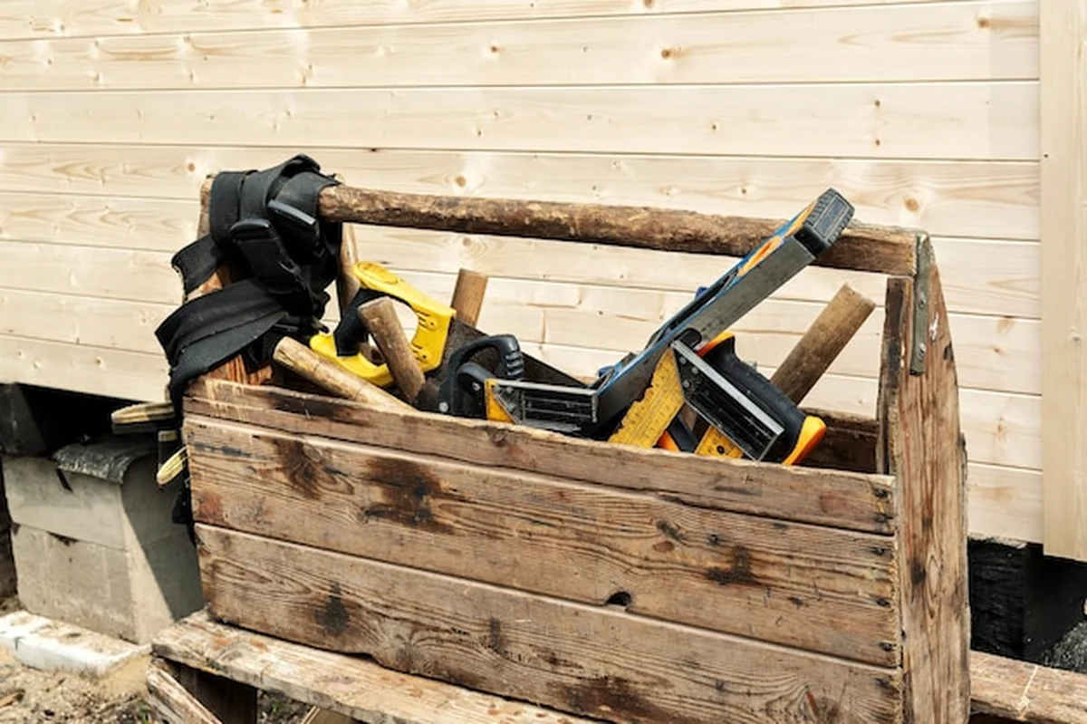 Stare drewniane pudełko z narzędziami na tle drewnianej ściany