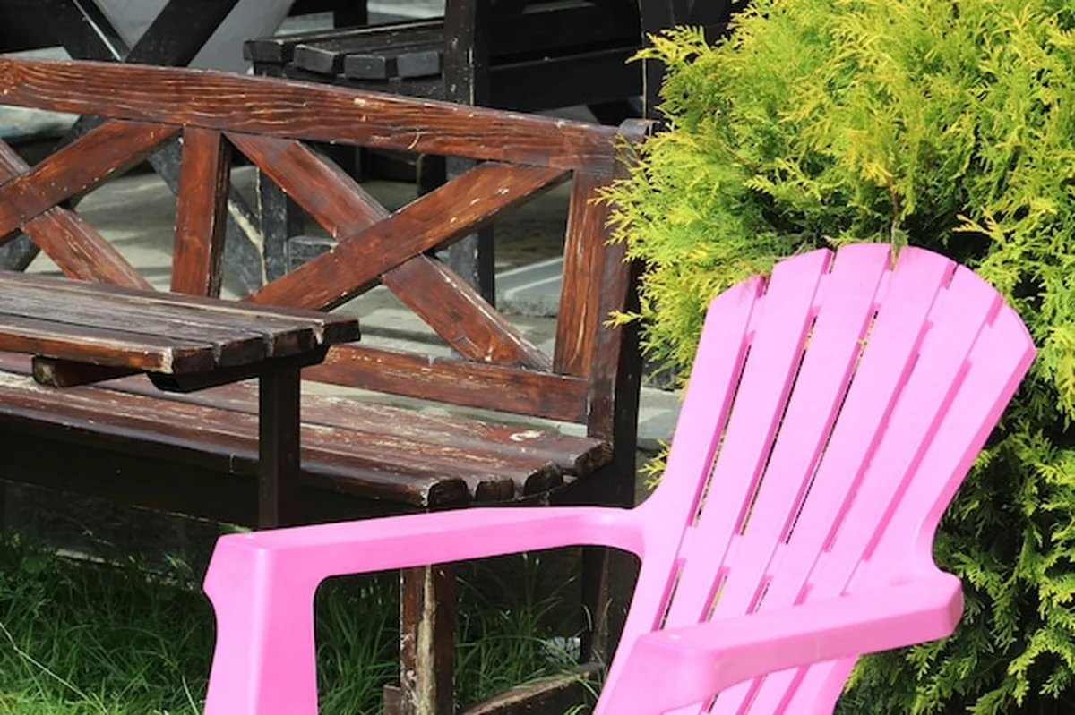 Puste plastikowe krzesło przy drewnianej ławce na podwórku