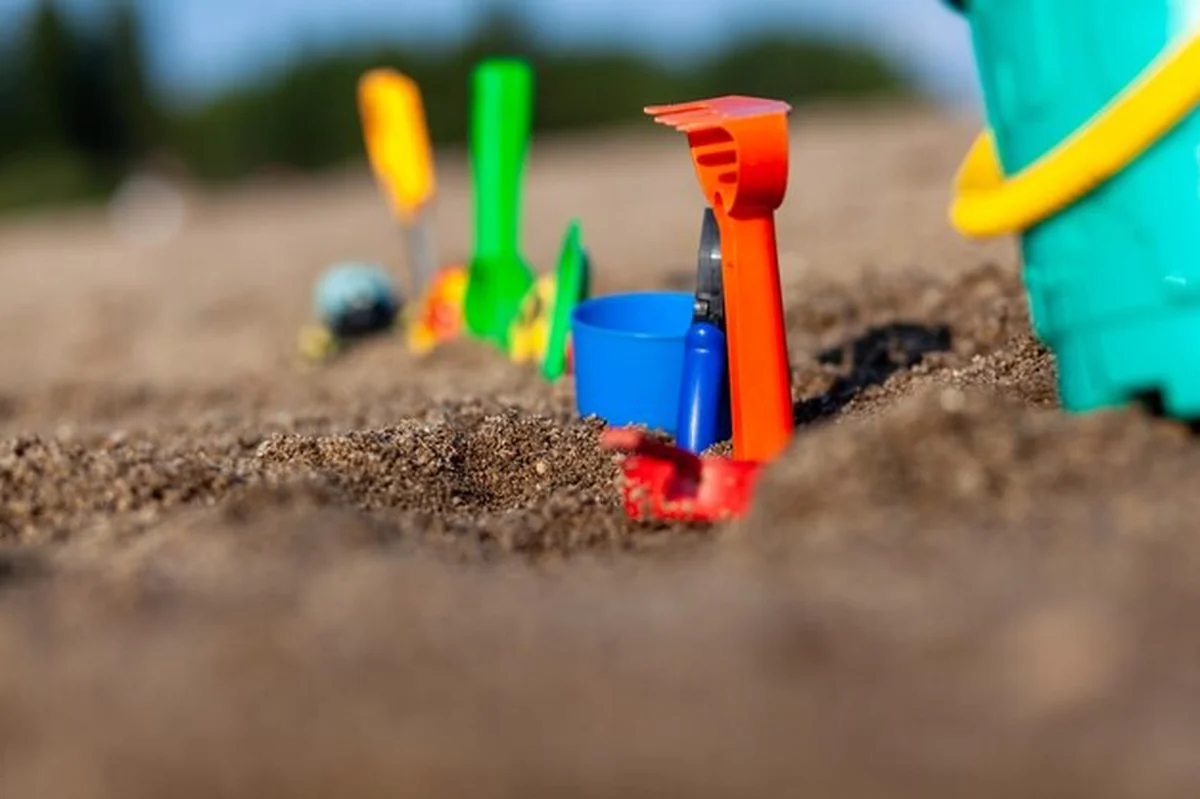 Zabawki dla dzieci na piasku - wiaderko i grabie na brzegu