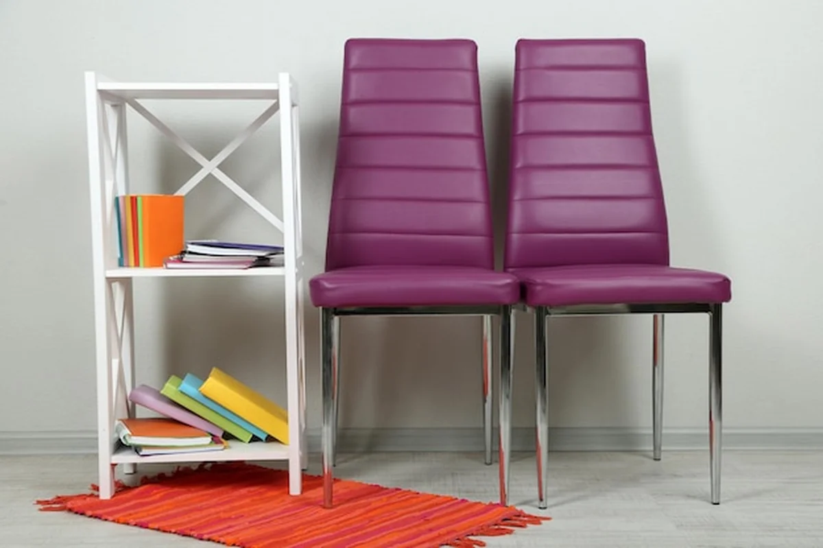 Wnętrze z kolorowymi krzesłami i książkami na drewnianym stojaku przed ścianą