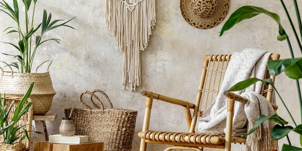 Kompozycja salonu w stylu boho z rattanowym fotelem, roślinami, donicami, dekoracją i makramą