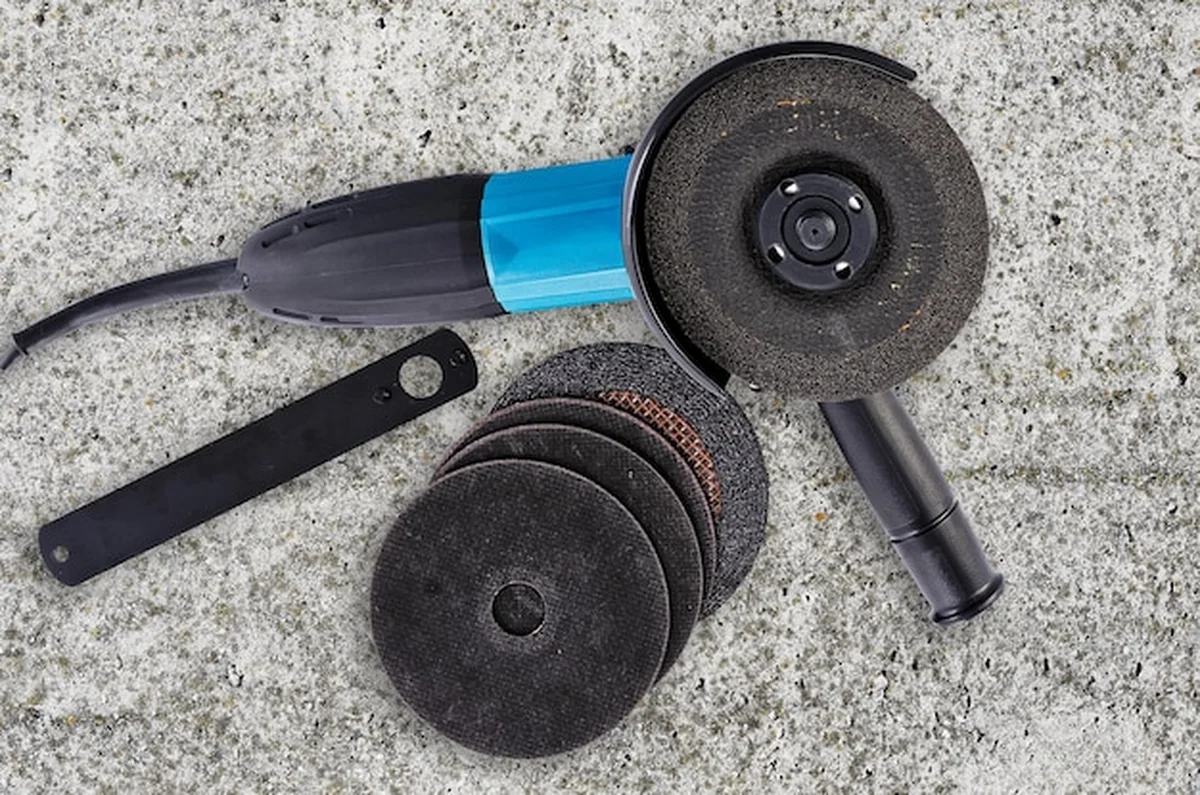 Szlifierka kątowa na betonowej podłodze z akcesoriami