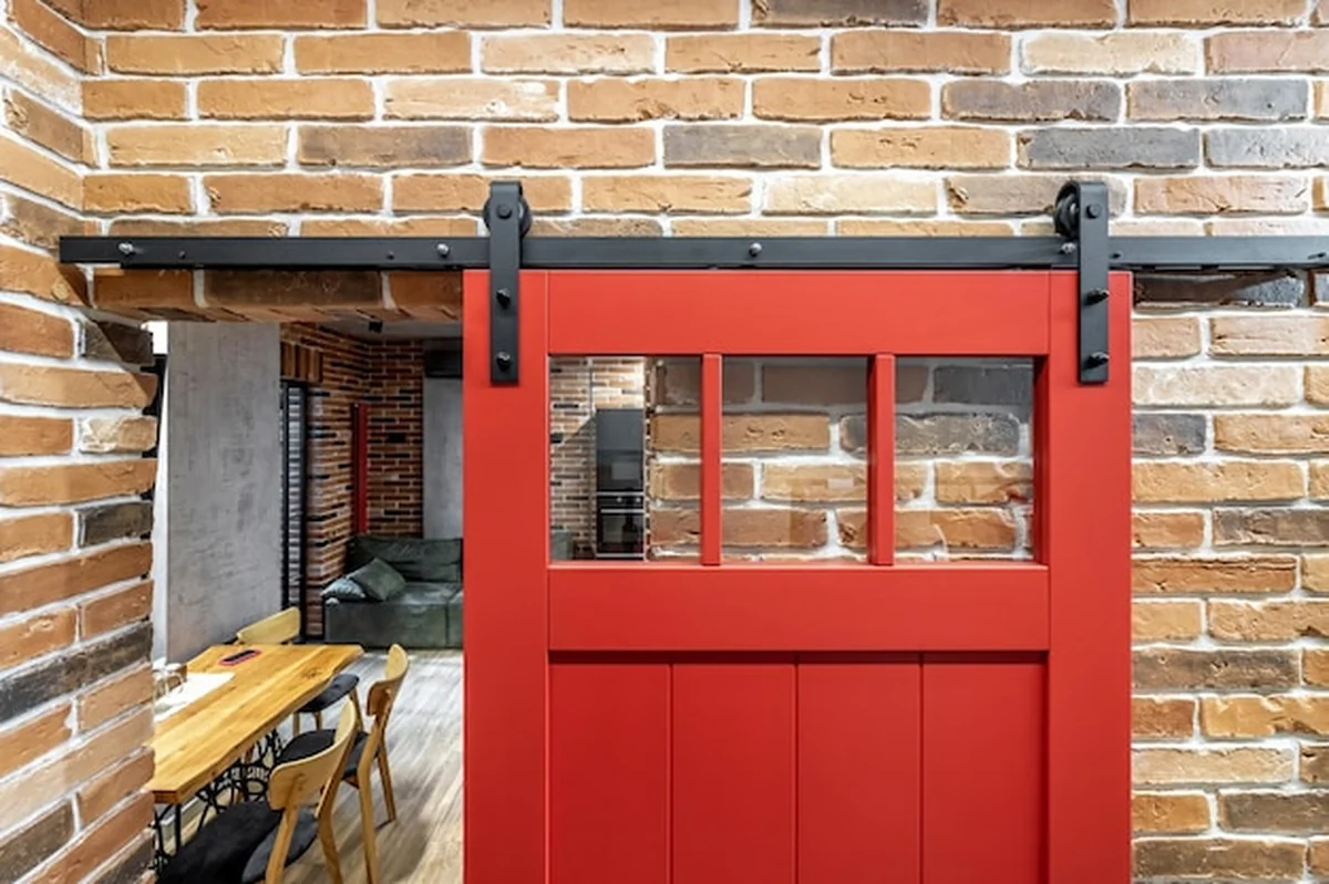 Wnętrze z czerwonymi drzwiami przesuwnymi i ścianą z czerwonej cegły