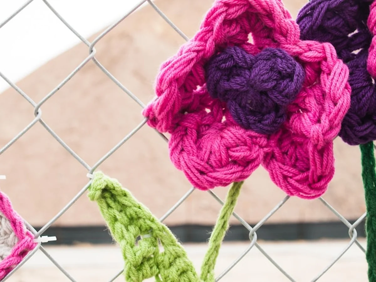 Płot budowlany z szydełkowanymi stworzeniami i kwiatami na placu budowy w Denver, Kolorado