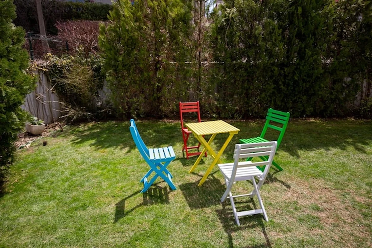 Zestaw ogrodowy z żółtym stołem i kolorowymi krzesłami