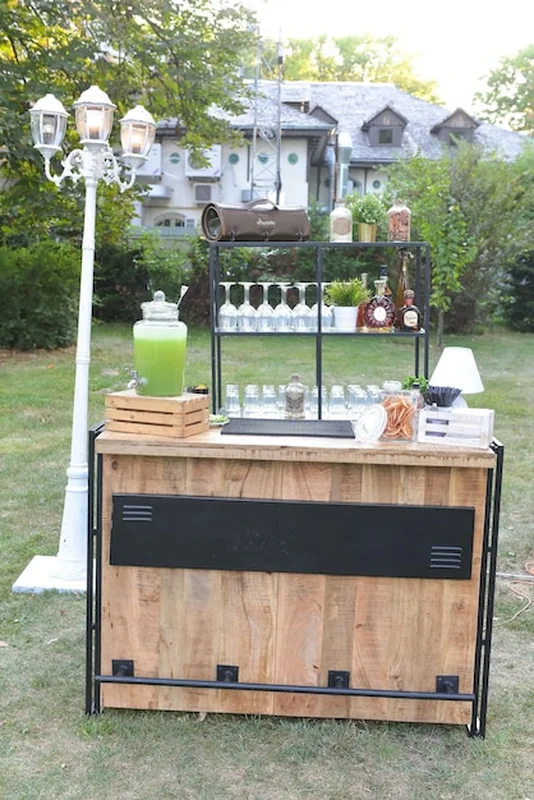 Drewniany bar z szklankami obok latarni w ogrodzie