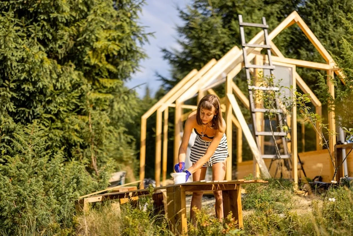 Kobieta budująca drewnianą szklarnię na podwórku