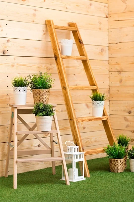 Drewniana drabina i rośliny w przytulnej przestrzeni z sztuczną trawą